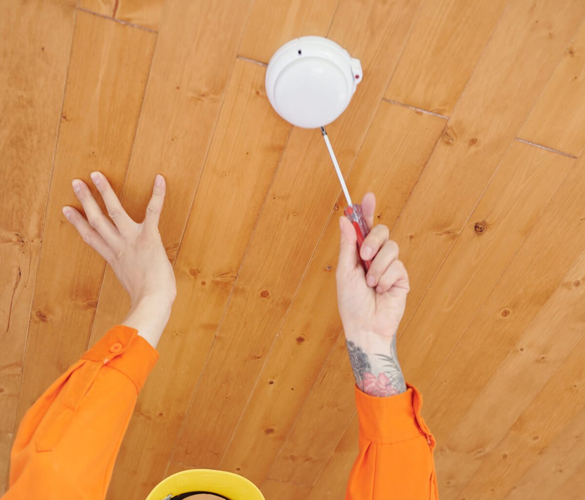 Technician installing smoke alarm at the ceiling